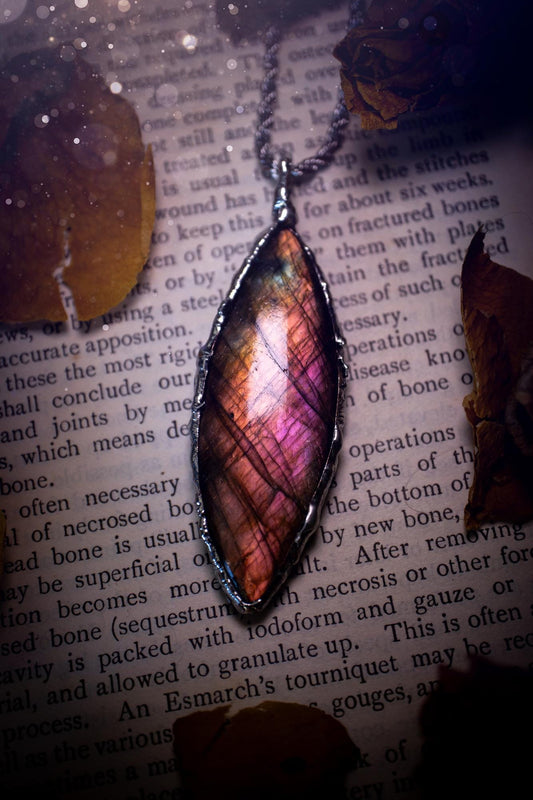 A beautiful, one of a kind, pink, purple and orange multi-flash Labradorite crystal pendant necklace. This pendant has been handmade using the soft solder method, also known as the tiffany technique used to create stained glass windows. Featuring the most stunning and natural Labradorite crystal which is full of purple and pink hues. The  pendant is suitable for gifting to any jewellery or crystal lover, or to simply add to your own collection. One of a kind jewellery, gothic and witchy gifts