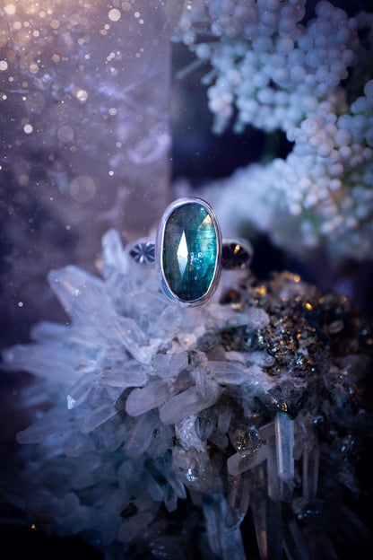 Beautiful and handcrafted, natural teal green kyanite crystal, staking ring. This stunning ring has been hand made using fine and sterling silver. It features a beautiful and natural teal green kyanite crystal that has rainbows and flash, such a gorgeous colour. The ring shank on this ring has been stamped with a gothic pattern to give it a one of a kind vibe. Ideal gift for that special person in your life, or for any crystal and jewellery lover. Hippy, witchy and gothic jewellery for the soul.