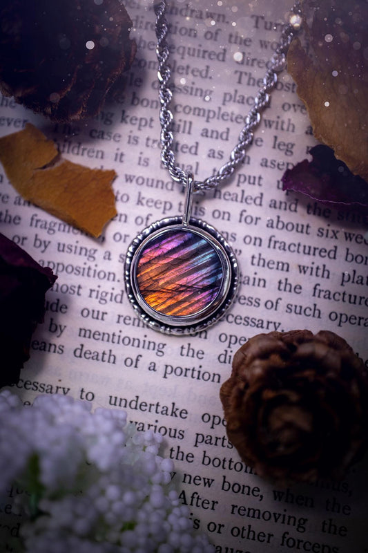 Beautiful and handcrafted, natural rainbow, pink, purple, and silver labradorite spectrolite pendant necklace. This beautiful pendant has been handmade using recycled fine and sterling silver. Featuring a round labradorite that is full of natural pinks, purples and silver hues. Around the crystal is a smooth inner bezel with gallery wire around as the outer bezel. This is the ideal piece of jewellery for a loved one or to treat yourself. Suitable for crystal and jewellery lovers. Gothic vibes.