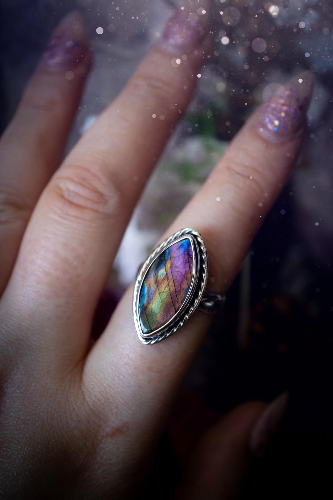 Handcrafted sterling silver statement ring featuring a stunning spectrolite labradorite crystal with vibrant flashes of purple, pink, and orange. This magical gemstone shimmers with an ethereal glow, making it a captivating piece for any jewellery collection. Ideal for crystal lovers, spiritual souls, and those drawn to unique, one-of-a-kind designs. A bold, mystical accessory perfect for expressing your inner light and energy. Gothic and handmade jewellery gifts, ideal for crystal lovers.