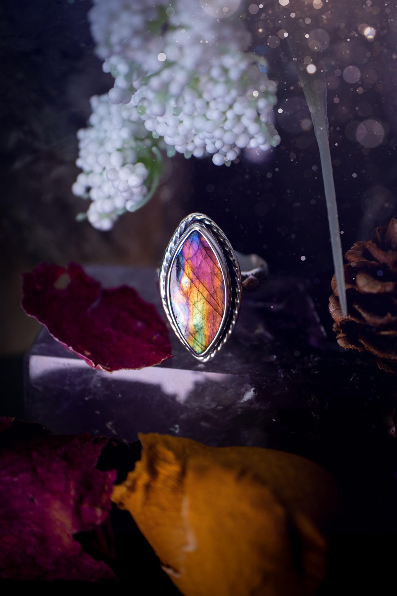 Handcrafted sterling silver statement ring featuring a stunning spectrolite labradorite crystal with vibrant flashes of purple, pink, and orange. This magical gemstone shimmers with an ethereal glow, making it a captivating piece for any jewellery collection. Ideal for crystal lovers, spiritual souls, and those drawn to unique, one-of-a-kind designs. A bold, mystical accessory perfect for expressing your inner light and energy. Gothic and handmade jewellery gifts, ideal for crystal lovers.