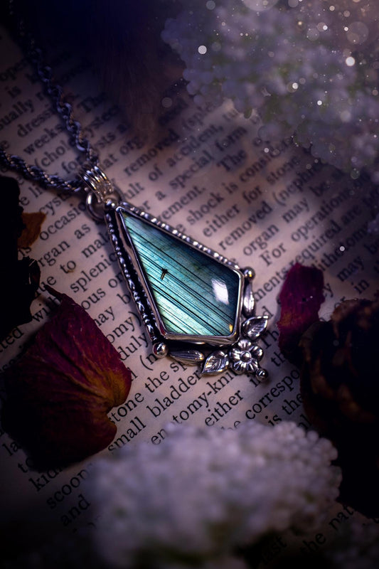 This stunning pendant necklace has been handcrafted using a mix of recycled fine and sterling silver. Featuring a beautiful and natural green and blue hued labradorite crystal that is full of flash! accompanying this magical crystal is a mix of fae inspired components such as little leaves, flower, silver balls and gothic gallery wire. A true bespoke piece with no other being the same! Ideal for any crystal and jewellery lover that loves a witchy and gothic vibe, along with the beauty of nature!
