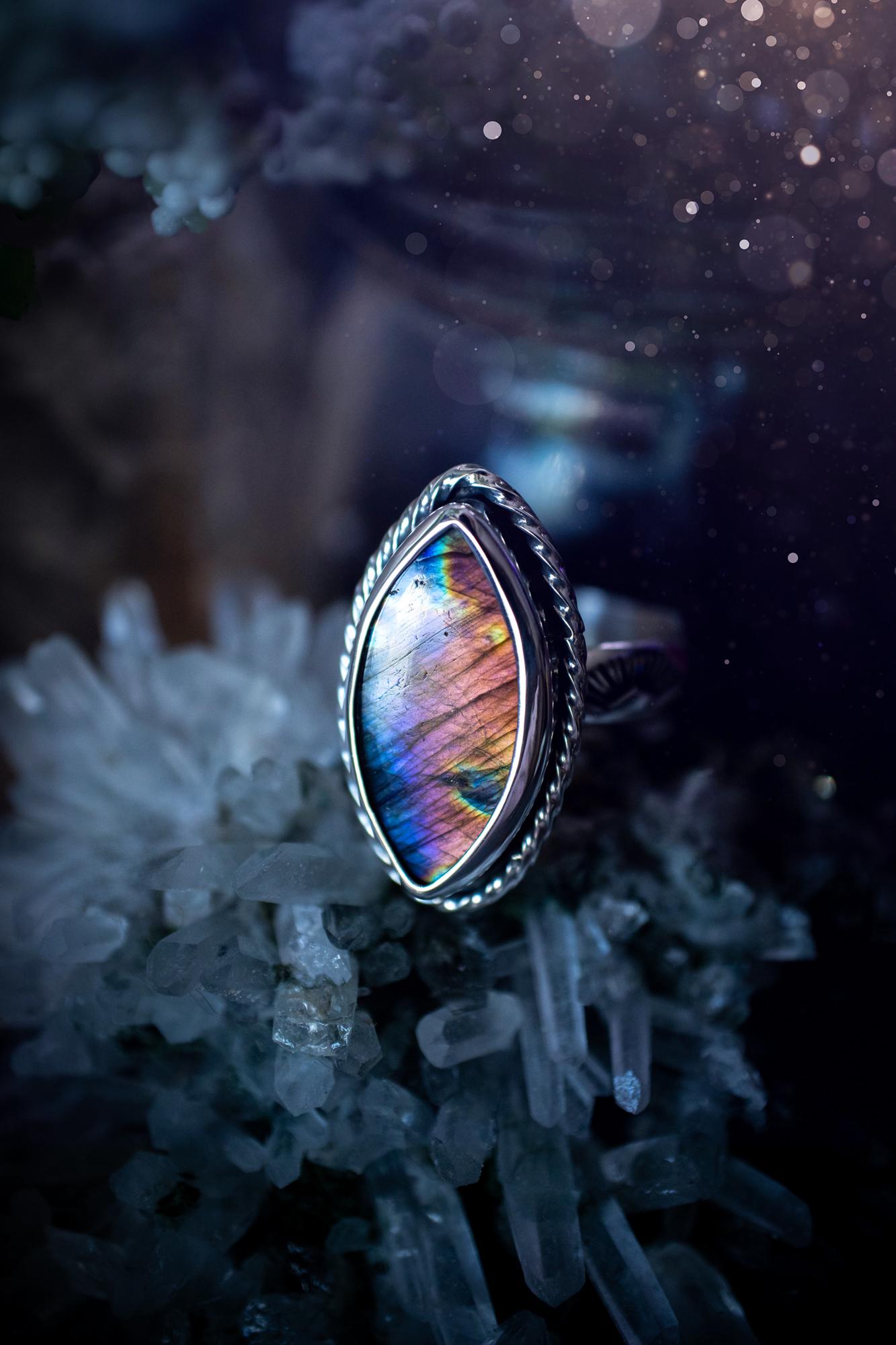 Handcrafted sterling silver statement ring featuring a stunning spectrolite labradorite crystal with vibrant flashes of purple, pink, and orange. This magical gemstone shimmers with an ethereal glow, making it a captivating piece for any jewellery collection. Ideal for crystal lovers, spiritual souls, and those drawn to unique, one-of-a-kind designs. A bold, mystical accessory perfect for expressing your inner light and energy. Gothic and handmade jewellery gifts, ideal for crystal lovers.