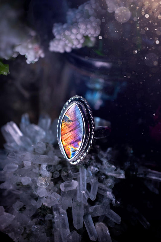 Handcrafted sterling silver statement ring featuring a stunning spectrolite labradorite crystal with vibrant flashes of purple, pink, and orange. This magical gemstone shimmers with an ethereal glow, making it a captivating piece for any jewellery collection. Ideal for crystal lovers, spiritual souls, and those drawn to unique, one-of-a-kind designs. A bold, mystical accessory perfect for expressing your inner light and energy. Gothic and handmade jewellery gifts, ideal for crystal lovers.
