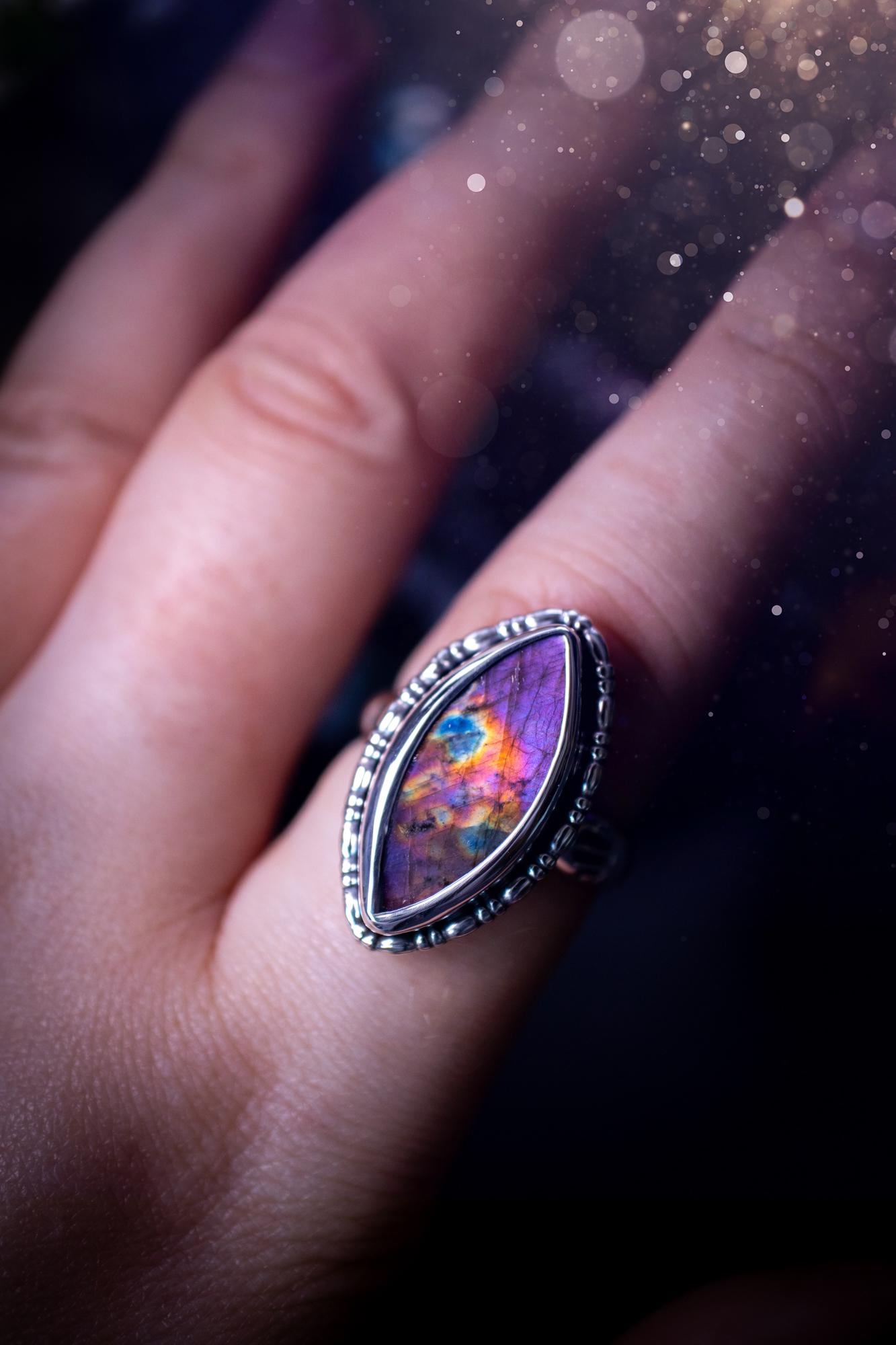 Handcrafted sterling silver statement ring featuring a stunning spectrolite labradorite crystal with vibrant flashes of purple, pink, and orange. This magical gemstone shimmers with an ethereal glow, making it a captivating piece for any jewellery collection. Ideal for crystal lovers, spiritual souls, and those drawn to unique, one-of-a-kind designs. A bold, mystical accessory perfect for expressing your inner light and energy. Gothic and handmade jewellery gifts, ideal for crystal lovers.