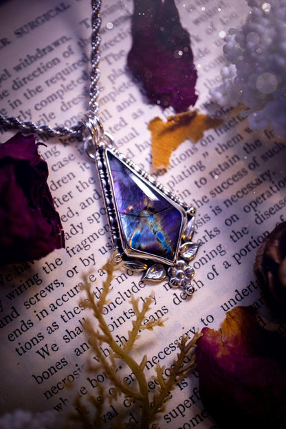 This stunning pendant necklace has been handcrafted using a mix of recycled fine and sterling silver. Featuring a beautiful and natural purple and pink hued labradorite crystal that is full of flash! accompanying this magical crystal is a mix of fae inspired components such as little leaves, flower, silver balls and gothic gallery wire. A true bespoke piece with no other being the same! Ideal for any crystal and jewellery lover that loves a witchy and gothic vibe, along with the beauty of nature