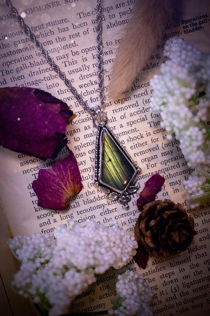 This stunning pendant necklace has been handcrafted using a mix of recycled fine and sterling silver. Featuring a beautiful and natural green and blue hued labradorite crystal that is full of flash! accompanying this magical crystal is a mix of fae inspired components such as little leaves, flower, silver balls and gothic gallery wire. A true bespoke piece with no other being the same! Ideal for any crystal and jewellery lover that loves a witchy and gothic vibe, along with the beauty of nature!