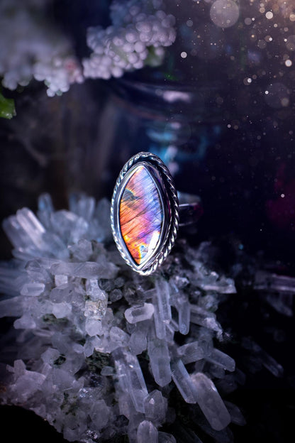 Handcrafted sterling silver statement ring featuring a stunning spectrolite labradorite crystal with vibrant flashes of purple, pink, and orange. This magical gemstone shimmers with an ethereal glow, making it a captivating piece for any jewellery collection. Ideal for crystal lovers, spiritual souls, and those drawn to unique, one-of-a-kind designs. A bold, mystical accessory perfect for expressing your inner light and energy. Gothic and handmade jewellery gifts, ideal for crystal lovers.