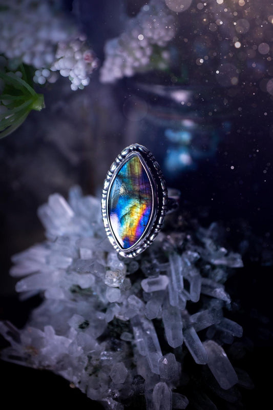 Handcrafted sterling silver statement ring featuring a stunning spectrolite labradorite crystal with vibrant flashes of purple, yellow, and blue. This magical gemstone shimmers with an ethereal glow, making it a captivating piece for any jewellery collection. Ideal for crystal lovers, spiritual souls, and those drawn to unique, one-of-a-kind designs. A bold, mystical accessory perfect for expressing your inner light and energy. Gothic and handmade jewellery gifts, ideal for crystal lovers.