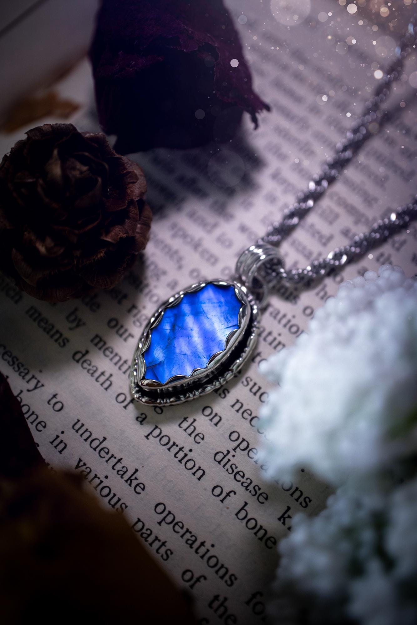 A handmade rainbow moonstone pendant necklace featuring a glowing, iridescent moonstone with blue and purple flashes. The stone is set in a scallop bezel, framed by bespoke gothic gallery wire that adds both hippy and witchy vibes. Crafted from sterling and fine silver, the pendant hangs on a silver chain, exuding mystical charm and alternative style. A one-of-a-kind piece with gothic, and magical energy. The ideal gift for crystal and jewellery lovers. Moonstone is the birthstone for June.