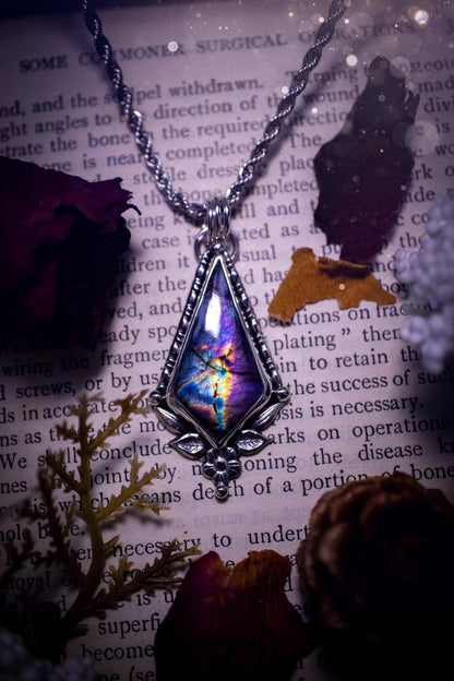 This stunning pendant necklace has been handcrafted using a mix of recycled fine and sterling silver. Featuring a beautiful and natural purple and pink hued labradorite crystal that is full of flash! accompanying this magical crystal is a mix of fae inspired components such as little leaves, flower, silver balls and gothic gallery wire. A true bespoke piece with no other being the same! Ideal for any crystal and jewellery lover that loves a witchy and gothic vibe, along with the beauty of nature