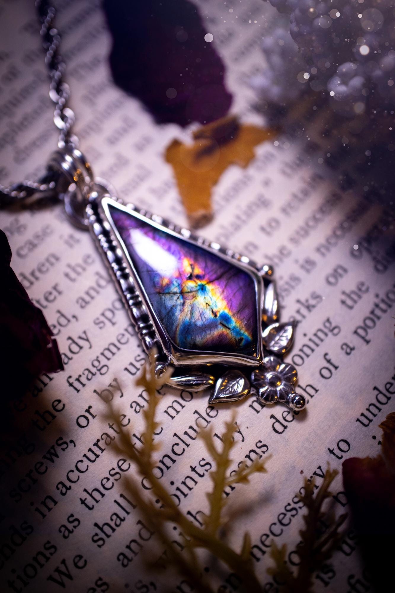 This stunning pendant necklace has been handcrafted using a mix of recycled fine and sterling silver. Featuring a beautiful and natural purple and pink hued labradorite crystal that is full of flash! accompanying this magical crystal is a mix of fae inspired components such as little leaves, flower, silver balls and gothic gallery wire. A true bespoke piece with no other being the same! Ideal for any crystal and jewellery lover that loves a witchy and gothic vibe, along with the beauty of nature