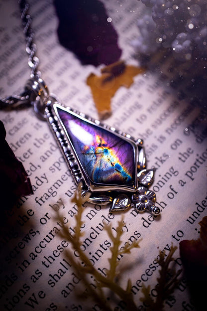 This stunning pendant necklace has been handcrafted using a mix of recycled fine and sterling silver. Featuring a beautiful and natural purple and pink hued labradorite crystal that is full of flash! accompanying this magical crystal is a mix of fae inspired components such as little leaves, flower, silver balls and gothic gallery wire. A true bespoke piece with no other being the same! Ideal for any crystal and jewellery lover that loves a witchy and gothic vibe, along with the beauty of nature