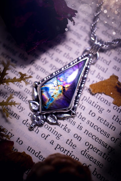 This stunning pendant necklace has been handcrafted using a mix of recycled fine and sterling silver. Featuring a beautiful and natural purple and pink hued labradorite crystal that is full of flash! accompanying this magical crystal is a mix of fae inspired components such as little leaves, flower, silver balls and gothic gallery wire. A true bespoke piece with no other being the same! Ideal for any crystal and jewellery lover that loves a witchy and gothic vibe, along with the beauty of nature