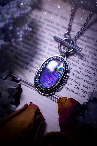 Beautifully handmade, amulet pendant necklace which features the most beautiful rainbow coloured, labradorite spectrolite crystal. This pendant has been handcrafted using a mix of fine and sterling silver. It features a scallop bezel with beaded, and hand carved smooth wire around the stone making this piece totally bespoke and one of a kind. The labradorite has an array of beautiful purples, blues and pinks. This pendant would be suitable for any crystal and jewellery lover, gothic and hippy!