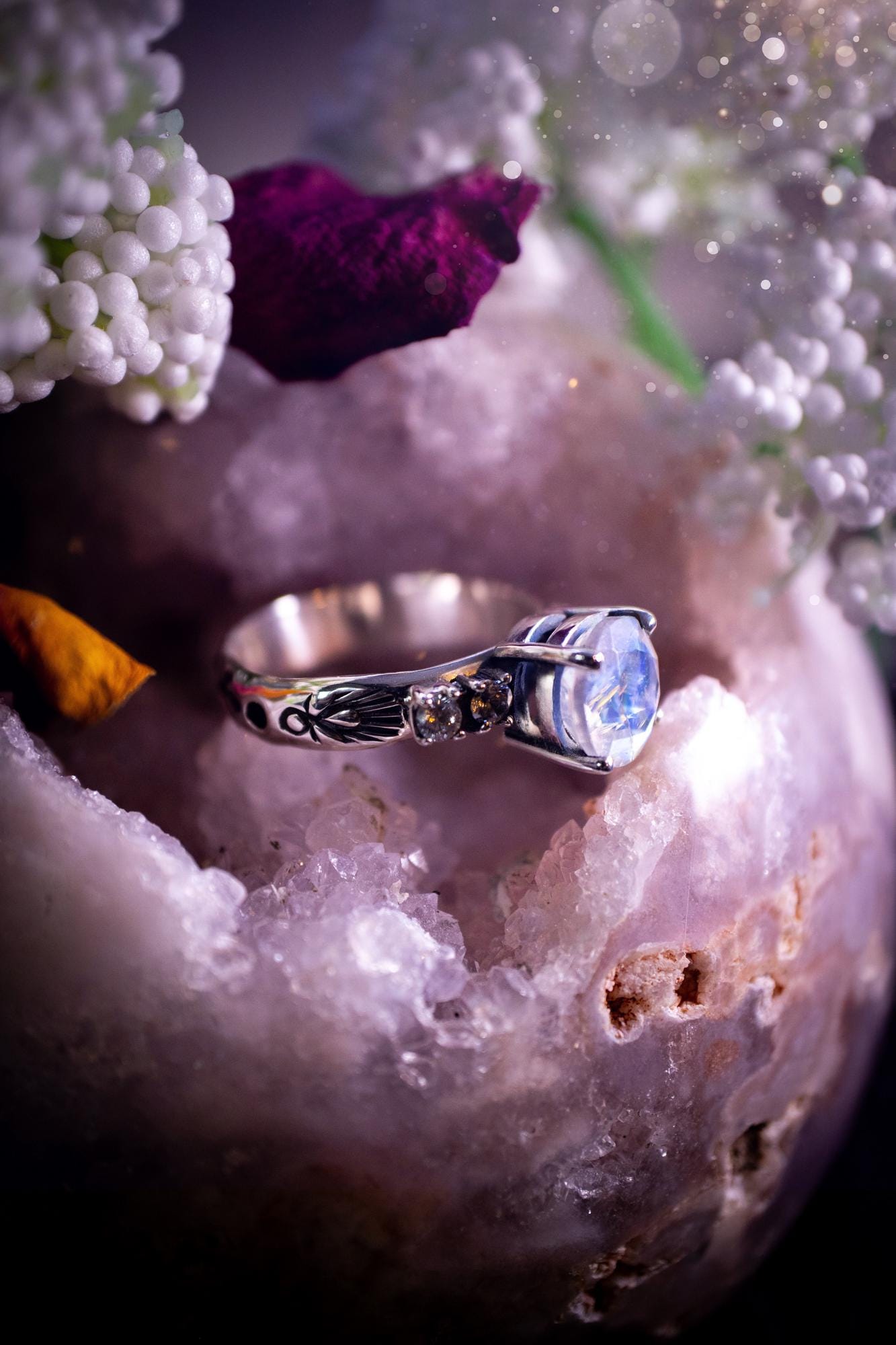 Beautifully handmade, and bespoke, natural rainbow moonstone statement ring. This one of a kind ring has been handmade using a mix of fine and sterling silver. Featuring a beautiful, flashy round, natural rainbow moonstone crystal that has stunning hues of blue, along with cubic zirconia to the sides of the crystal. The ring band is stamped with unique detailing. The ideal treat and gift for anyone who is a lover of crystals and jewellery. This ring is full of gothic and witchy vibes!