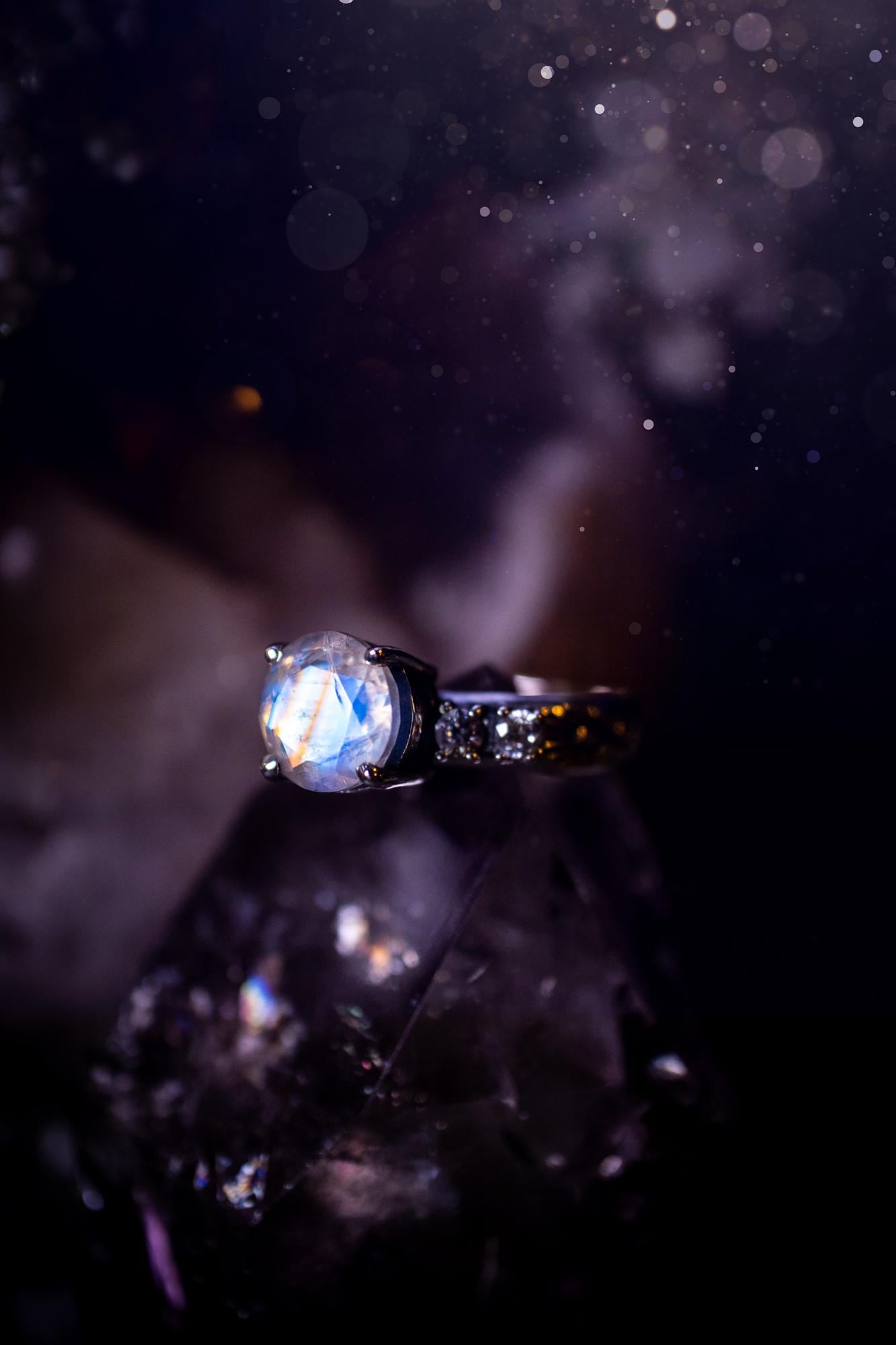 Beautifully handmade, and bespoke, natural rainbow moonstone statement ring. This one of a kind ring has been handmade using a mix of fine and sterling silver. Featuring a beautiful, flashy round, natural rainbow moonstone crystal that has stunning hues of blue, along with cubic zirconia to the sides of the crystal. The ring band is stamped with unique detailing. The ideal treat and gift for anyone who is a lover of crystals and jewellery. This ring is full of gothic and witchy vibes!