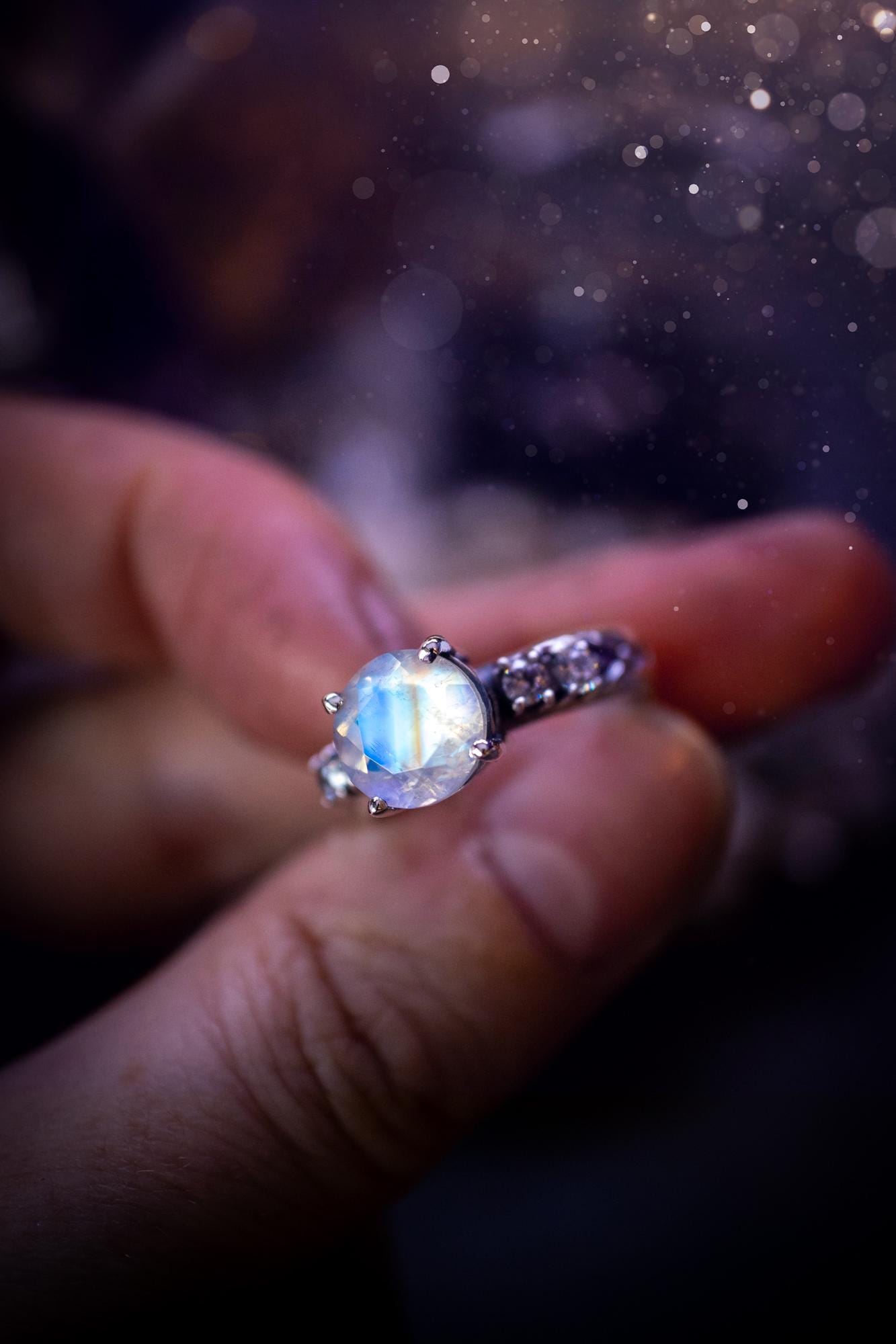 Beautifully handmade, and bespoke, natural rainbow moonstone statement ring. This one of a kind ring has been handmade using a mix of fine and sterling silver. Featuring a beautiful, flashy round, natural rainbow moonstone crystal that has stunning hues of blue, along with cubic zirconia to the sides of the crystal. The ring band is stamped with unique detailing. The ideal treat and gift for anyone who is a lover of crystals and jewellery. This ring is full of gothic and witchy vibes!