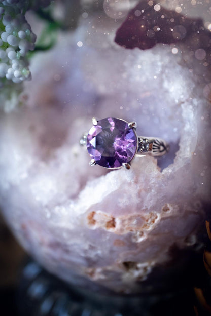Beautifully handmade, and bespoke, natural amethyst crystal statement ring. This one of a kind ring has been handmade using a mix of fine and sterling silver. Featuring a beautiful, sparkly, round, natural amethyst crystal that has stunning hues of purple, along with cubic zirconia to the sides of the crystal. The ring band is stamped with unique detailing. The ideal treat and gift for anyone who is a lover of crystals and jewellery. This ring is full of gothic and witchy vibes! engagement ring