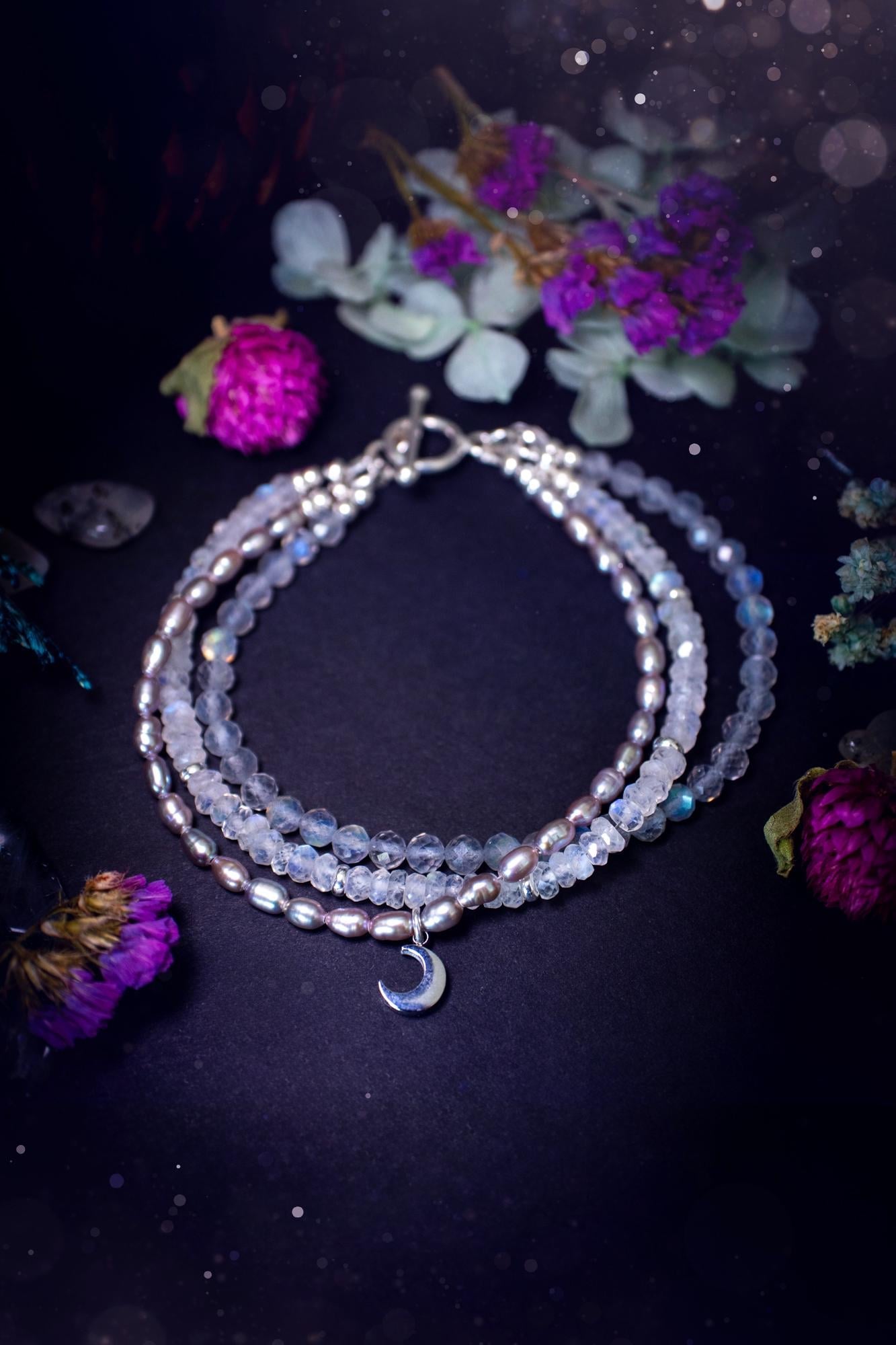 Stunning and handcrafted, triple crystal beaded bracelet. This beautiful bracelet consists of three bracelets in one all held together with a sterling silver t-bar toggle clasp. Featuring stunning flashy rainbow moonstone, light coloured labradorite, and grey to purple fresh water pearls. The findings on this bracelet are sterling silver, with a stainless steel moon charm. This piece is totally bespoke and full of celestial vibes. Ideal for any crystal and jewellery lover. Witchy and gothic