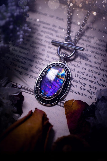 Beautifully handmade, amulet pendant necklace which features the most beautiful rainbow coloured, labradorite spectrolite crystal. This pendant has been handcrafted using a mix of fine and sterling silver. It features a scallop bezel with beaded, and hand carved smooth wire around the stone making this piece totally bespoke and one of a kind. The labradorite has an array of beautiful purples, blues and pinks. This pendant would be suitable for any crystal and jewellery lover, gothic and hippy!