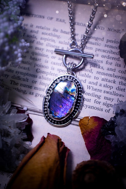 Beautifully handmade, amulet pendant necklace which features the most beautiful rainbow coloured, labradorite spectrolite crystal. This pendant has been handcrafted using a mix of fine and sterling silver. It features a scallop bezel with beaded, and hand carved smooth wire around the stone making this piece totally bespoke and one of a kind. The labradorite has an array of beautiful purples, blues and pinks. This pendant would be suitable for any crystal and jewellery lover, gothic and hippy!
