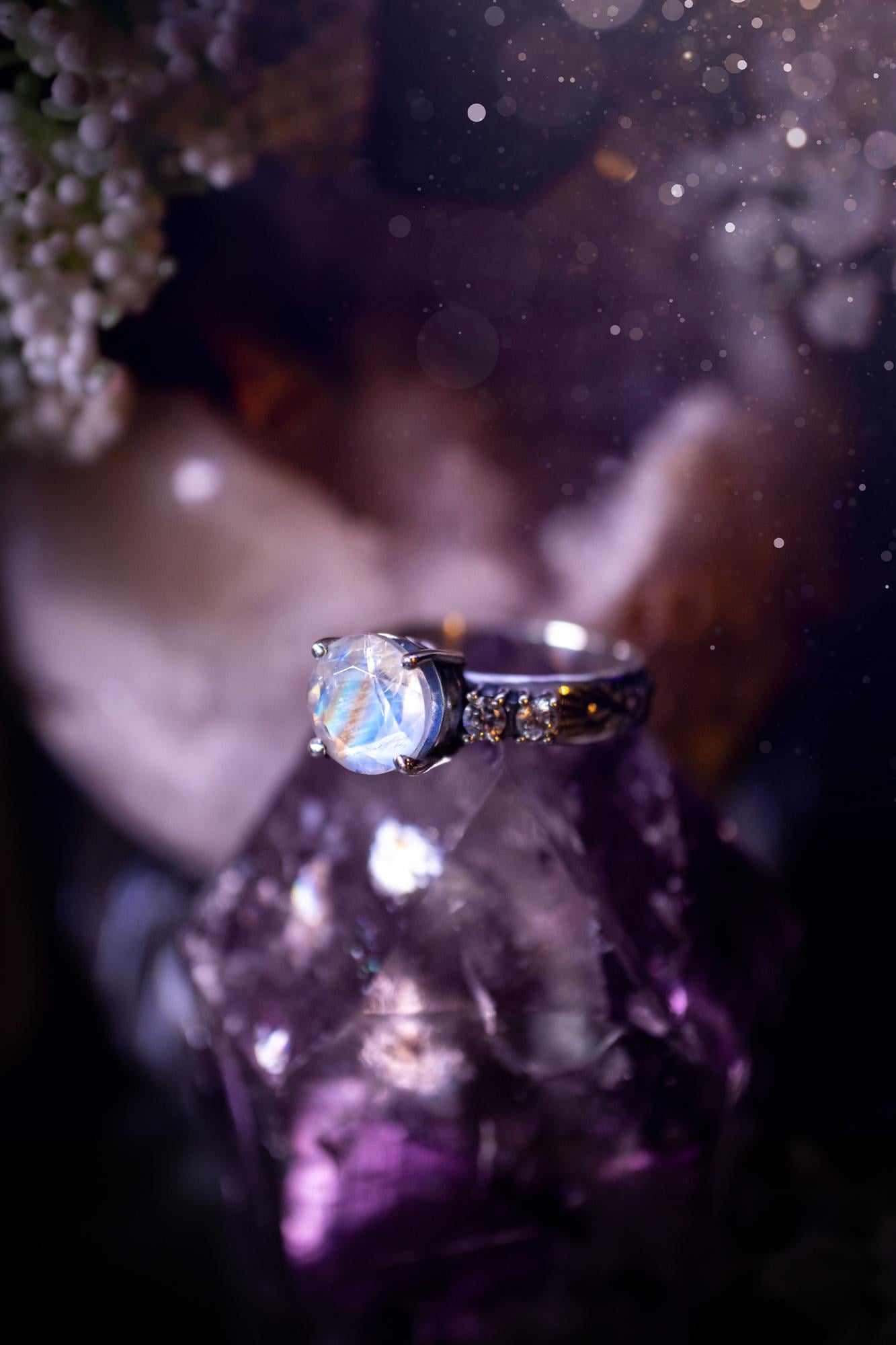 Beautifully handmade, and bespoke, natural rainbow moonstone statement ring. This one of a kind ring has been handmade using a mix of fine and sterling silver. Featuring a beautiful, flashy round, natural rainbow moonstone crystal that has stunning hues of blue, along with cubic zirconia to the sides of the crystal. The ring band is stamped with unique detailing. The ideal treat and gift for anyone who is a lover of crystals and jewellery. This ring is full of gothic and witchy vibes!