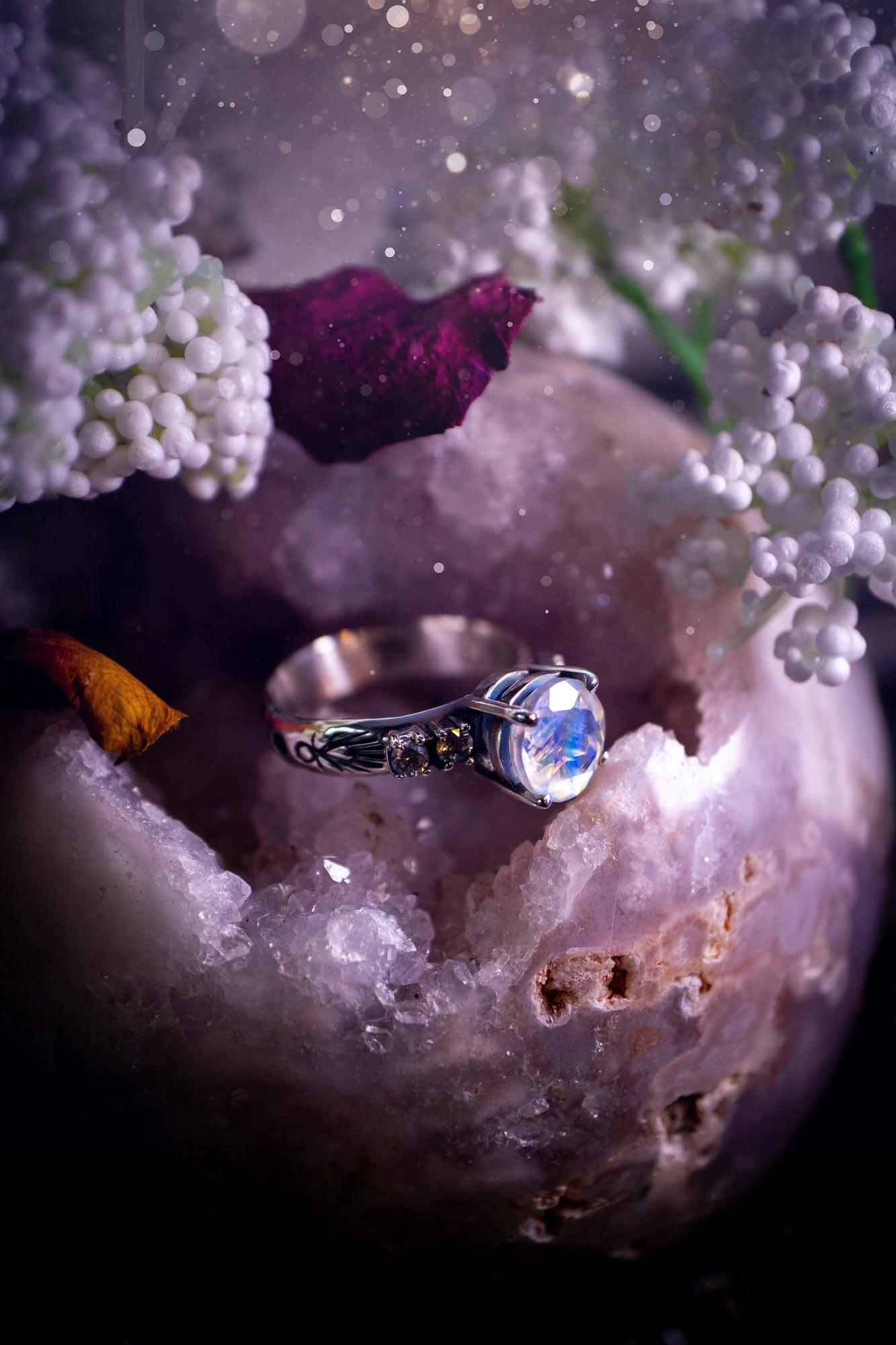 Beautifully handmade, and bespoke, natural rainbow moonstone statement ring. This one of a kind ring has been handmade using a mix of fine and sterling silver. Featuring a beautiful, flashy round, natural rainbow moonstone crystal that has stunning hues of blue, along with cubic zirconia to the sides of the crystal. The ring band is stamped with unique detailing. The ideal treat and gift for anyone who is a lover of crystals and jewellery. This ring is full of gothic and witchy vibes!