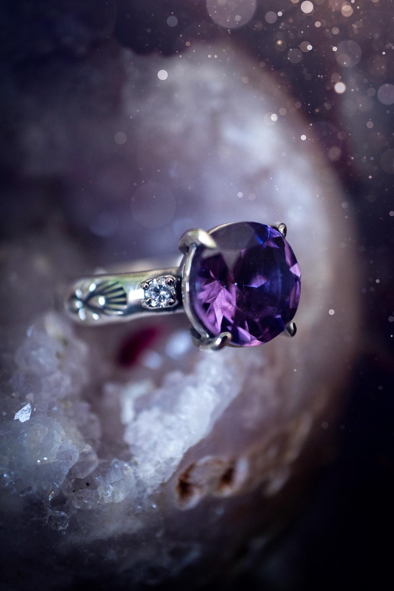 Beautifully handmade, and bespoke, natural amethyst crystal statement ring. This one of a kind ring has been handmade using a mix of fine and sterling silver. Featuring a beautiful, sparkly, round, natural amethyst crystal that has stunning hues of purple, along with cubic zirconia to the sides of the crystal. The ring band is stamped with unique detailing. The ideal treat and gift for anyone who is a lover of crystals and jewellery. This ring is full of gothic and witchy vibes! engagement ring