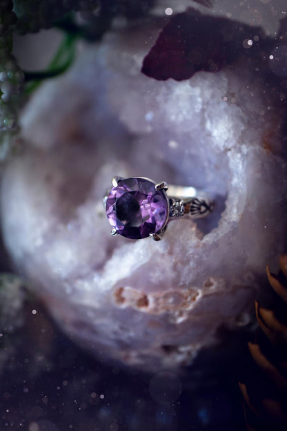 Beautifully handmade, and bespoke, natural amethyst crystal statement ring. This one of a kind ring has been handmade using a mix of fine and sterling silver. Featuring a beautiful, sparkly, round, natural amethyst crystal that has stunning hues of purple, along with cubic zirconia to the sides of the crystal. The ring band is stamped with unique detailing. The ideal treat and gift for anyone who is a lover of crystals and jewellery. This ring is full of gothic and witchy vibes! engagement ring