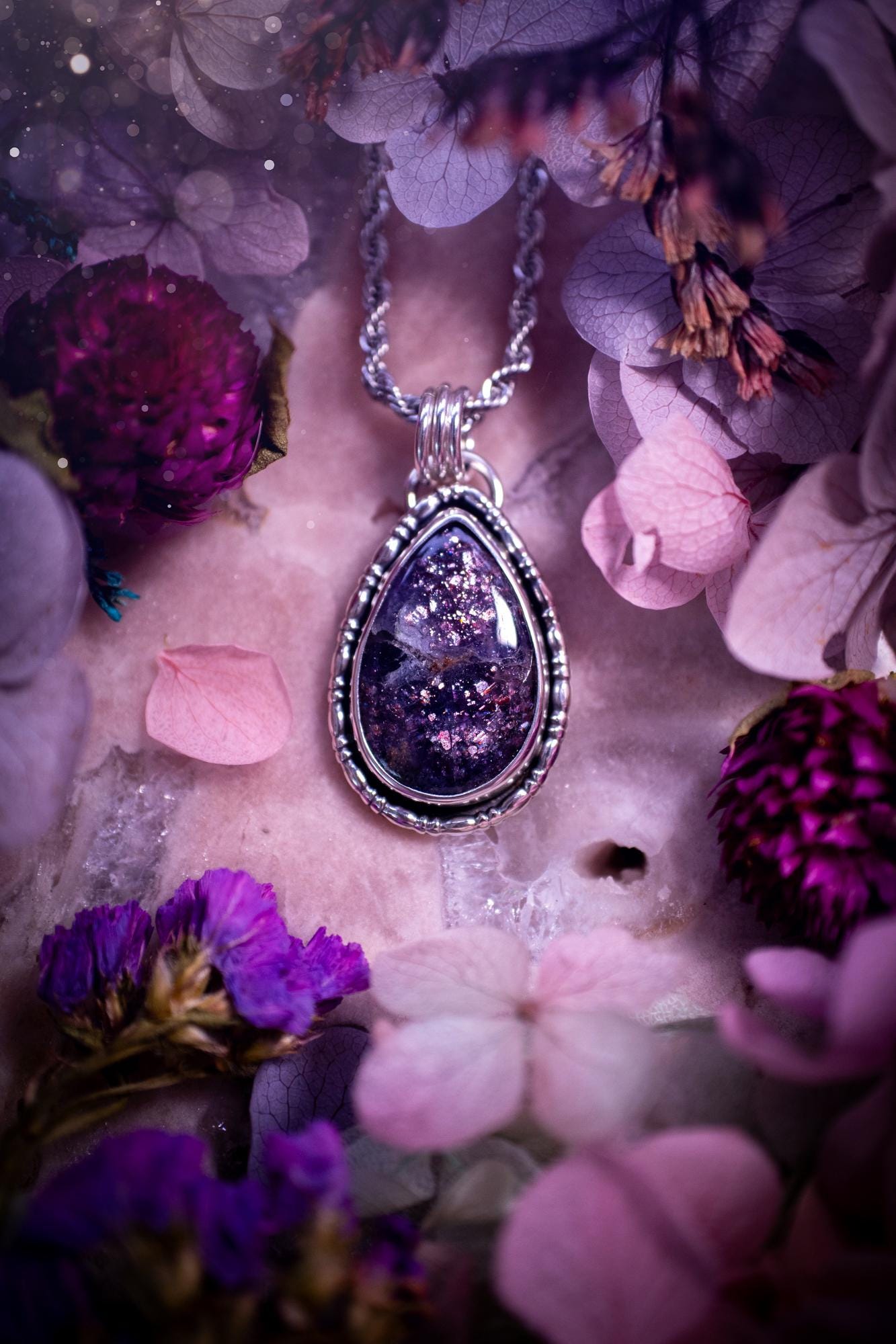 Stunning and handcrafted, natural Iolite sunstone, crystal pendant necklace. This beautiful pendant features a very sparkly iolite sunstone crystal that looks just like the galaxy, full of sparkle and pink shimmer. Made from a mix of sterling and fine silver, this piece is full of gothic vibes and has a gothic gallery wire around the crystal. Small and dainty. This piece would be suitable for gifting to jewellery and crystal lovers. Very witchy, gothic and hippy!