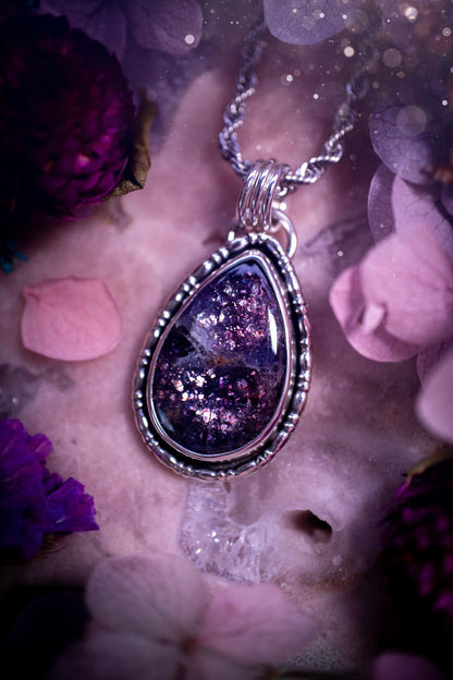 Stunning and handcrafted, natural Iolite sunstone, crystal pendant necklace. This beautiful pendant features a very sparkly iolite sunstone crystal that looks just like the galaxy, full of sparkle and pink shimmer. Made from a mix of sterling and fine silver, this piece is full of gothic vibes and has a gothic gallery wire around the crystal. Small and dainty. This piece would be suitable for gifting to jewellery and crystal lovers. Very witchy, gothic and hippy!