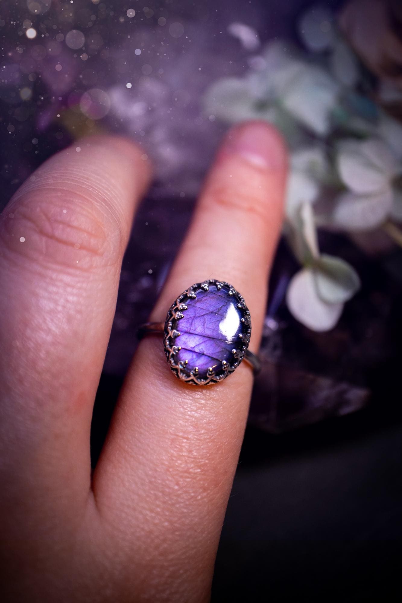 Handmade and very gothic, natural purple labradorite, sterling silver ring. This minimalist ring features a very pretty and flashy labradorite crystal that has a rich and vibrant purple colour. Around the crystal is a beautifully detail, gothic bezel that has been polished to a high lustre. The crystal is mounted on a 1.50mm ring shank. This ring would be ideal for anyone who loves jewellery and crystals, or who has a gothic and witchy style. A beautiful piece of jewellery to add to a collection