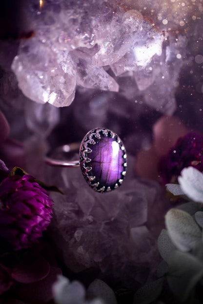 Handmade and very gothic, natural purple labradorite, sterling silver ring. This minimalist ring features a very pretty and flashy labradorite crystal that has a rich and vibrant purple colour. Around the crystal is a beautifully detail, gothic bezel that has been polished to a high lustre. The crystal is mounted on a 1.50mm ring shank. This ring would be ideal for anyone who loves jewellery and crystals, or who has a gothic and witchy style. A beautiful piece of jewellery to add to a collection