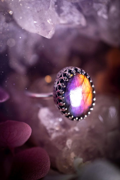 Handmade and very gothic, natural purple labradorite, sterling silver ring. This minimalist ring features a very pretty and flashy labradorite crystal that has a rich and vibrant purple colour. Around the crystal is a beautifully detail, gothic bezel that has been polished to a high lustre. The crystal is mounted on a 1.50mm ring shank. This ring would be ideal for anyone who loves jewellery and crystals, or who has a gothic and witchy style. A beautiful piece of jewellery to add to a collection