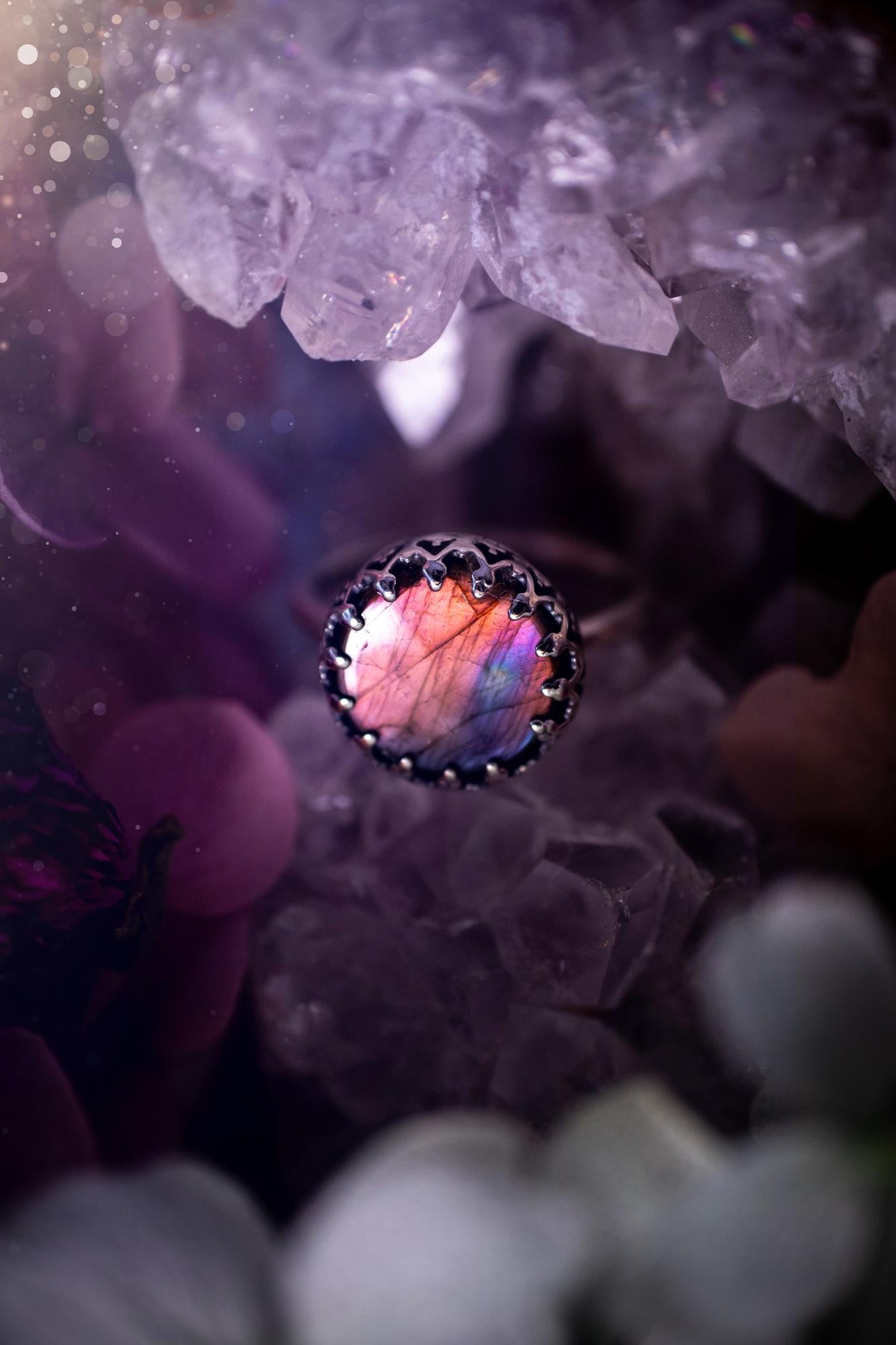 Handmade and very gothic, natural purple labradorite, sterling silver ring. This minimalist ring features a very pretty and flashy labradorite crystal that has a rich and vibrant purple colour. Around the crystal is a beautifully detail, gothic bezel that has been polished to a high lustre. The crystal is mounted on a 1.50mm ring shank. This ring would be ideal for anyone who loves jewellery and crystals, or who has a gothic and witchy style. A beautiful piece of jewellery to add to a collection