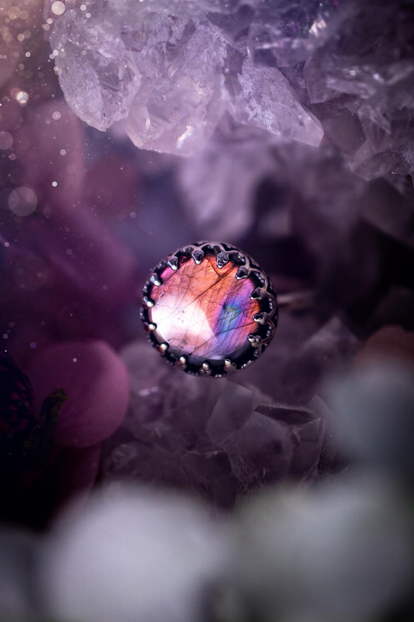 Handmade and very gothic, natural purple labradorite, sterling silver ring. This minimalist ring features a very pretty and flashy labradorite crystal that has a rich and vibrant purple colour. Around the crystal is a beautifully detail, gothic bezel that has been polished to a high lustre. The crystal is mounted on a 1.50mm ring shank. This ring would be ideal for anyone who loves jewellery and crystals, or who has a gothic and witchy style. A beautiful piece of jewellery to add to a collection