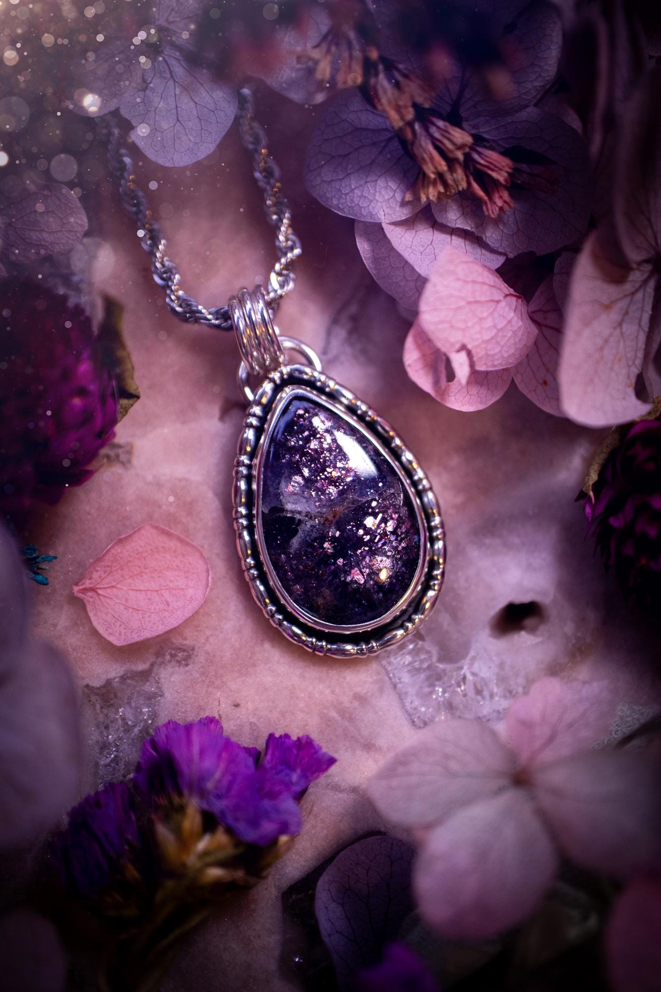 Stunning and handcrafted, natural Iolite sunstone, crystal pendant necklace. This beautiful pendant features a very sparkly iolite sunstone crystal that looks just like the galaxy, full of sparkle and pink shimmer. Made from a mix of sterling and fine silver, this piece is full of gothic vibes and has a gothic gallery wire around the crystal. Small and dainty. This piece would be suitable for gifting to jewellery and crystal lovers. Very witchy, gothic and hippy!