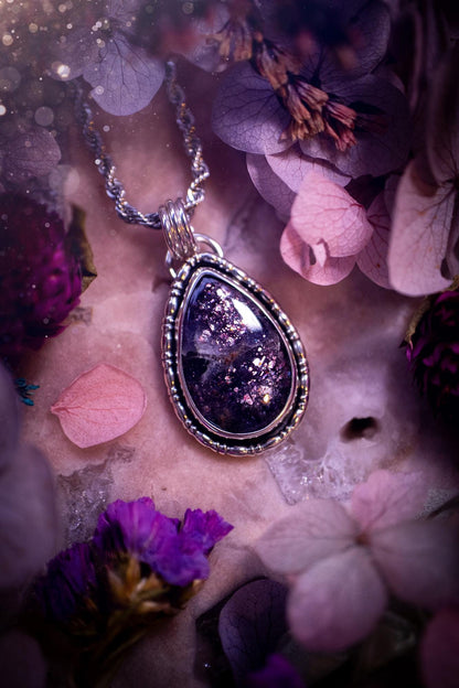 Stunning and handcrafted, natural Iolite sunstone, crystal pendant necklace. This beautiful pendant features a very sparkly iolite sunstone crystal that looks just like the galaxy, full of sparkle and pink shimmer. Made from a mix of sterling and fine silver, this piece is full of gothic vibes and has a gothic gallery wire around the crystal. Small and dainty. This piece would be suitable for gifting to jewellery and crystal lovers. Very witchy, gothic and hippy!