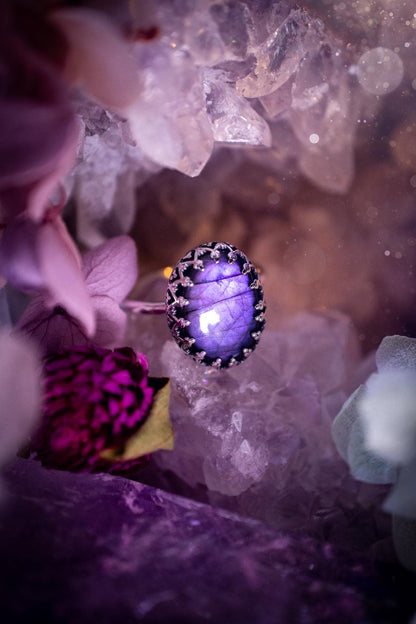 Handmade and very gothic, natural purple labradorite, sterling silver ring. This minimalist ring features a very pretty and flashy labradorite crystal that has a rich and vibrant purple colour. Around the crystal is a beautifully detail, gothic bezel that has been polished to a high lustre. The crystal is mounted on a 1.50mm ring shank. This ring would be ideal for anyone who loves jewellery and crystals, or who has a gothic and witchy style. A beautiful piece of jewellery to add to a collection