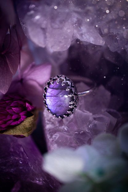 Handmade and very gothic, natural purple labradorite, sterling silver ring. This minimalist ring features a very pretty and flashy labradorite crystal that has a rich and vibrant purple colour. Around the crystal is a beautifully detail, gothic bezel that has been polished to a high lustre. The crystal is mounted on a 1.50mm ring shank. This ring would be ideal for anyone who loves jewellery and crystals, or who has a gothic and witchy style. A beautiful piece of jewellery to add to a collection