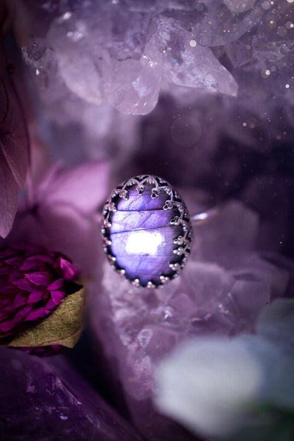Handmade and very gothic, natural purple labradorite, sterling silver ring. This minimalist ring features a very pretty and flashy labradorite crystal that has a rich and vibrant purple colour. Around the crystal is a beautifully detail, gothic bezel that has been polished to a high lustre. The crystal is mounted on a 1.50mm ring shank. This ring would be ideal for anyone who loves jewellery and crystals, or who has a gothic and witchy style. A beautiful piece of jewellery to add to a collection