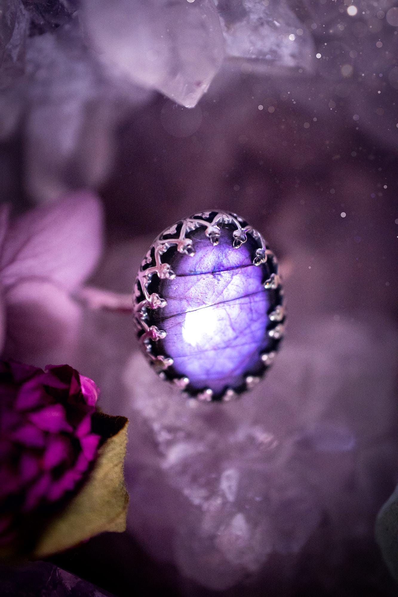 Handmade and very gothic, natural purple labradorite, sterling silver ring. This minimalist ring features a very pretty and flashy labradorite crystal that has a rich and vibrant purple colour. Around the crystal is a beautifully detail, gothic bezel that has been polished to a high lustre. The crystal is mounted on a 1.50mm ring shank. This ring would be ideal for anyone who loves jewellery and crystals, or who has a gothic and witchy style. A beautiful piece of jewellery to add to a collection