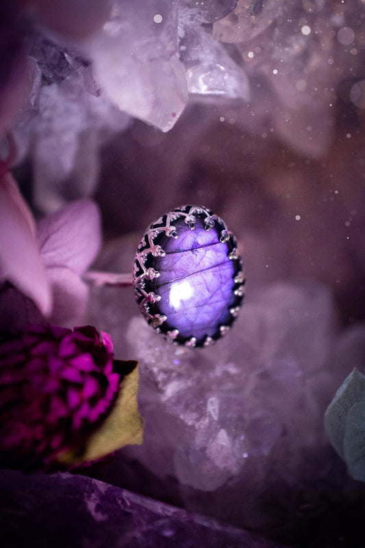 Handmade and very gothic, natural purple labradorite, sterling silver ring. This minimalist ring features a very pretty and flashy labradorite crystal that has a rich and vibrant purple colour. Around the crystal is a beautifully detail, gothic bezel that has been polished to a high lustre. The crystal is mounted on a 1.50mm ring shank. This ring would be ideal for anyone who loves jewellery and crystals, or who has a gothic and witchy style. A beautiful piece of jewellery to add to a collection