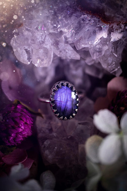 Handmade and very gothic, natural purple labradorite, sterling silver ring. This minimalist ring features a very pretty and flashy labradorite crystal that has a rich and vibrant purple colour. Around the crystal is a beautifully detail, gothic bezel that has been polished to a high lustre. The crystal is mounted on a 1.50mm ring shank. This ring would be ideal for anyone who loves jewellery and crystals, or who has a gothic and witchy style. A beautiful piece of jewellery to add to a collection