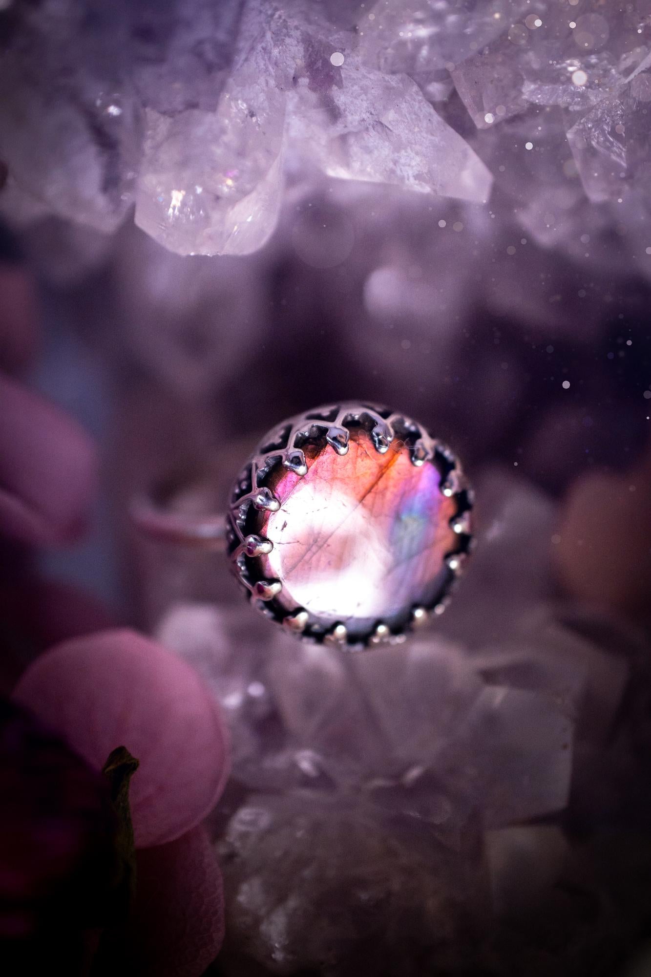 Handmade and very gothic, natural purple labradorite, sterling silver ring. This minimalist ring features a very pretty and flashy labradorite crystal that has a rich and vibrant purple colour. Around the crystal is a beautifully detail, gothic bezel that has been polished to a high lustre. The crystal is mounted on a 1.50mm ring shank. This ring would be ideal for anyone who loves jewellery and crystals, or who has a gothic and witchy style. A beautiful piece of jewellery to add to a collection