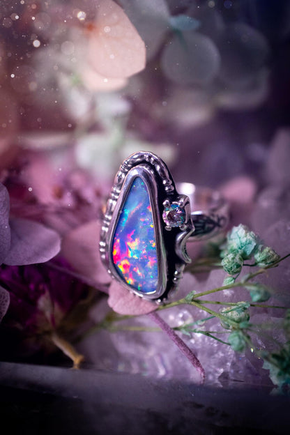 Handmade and totally bespoke, Australian Opal doublet, celestial style ring. This mini statement ring has been handmade using fine and sterling silver. Featuring a very beautiful and bold Australian Opal doublet that is full of colour play with lilac, reds, blues and greens that are super flashy! The ring is of a celestial style with a little moon and aurora coloured cubic zirconia to the side. This little ring would be suitable for anyone who loves crystals, opals and jewellery! Gothic vibes