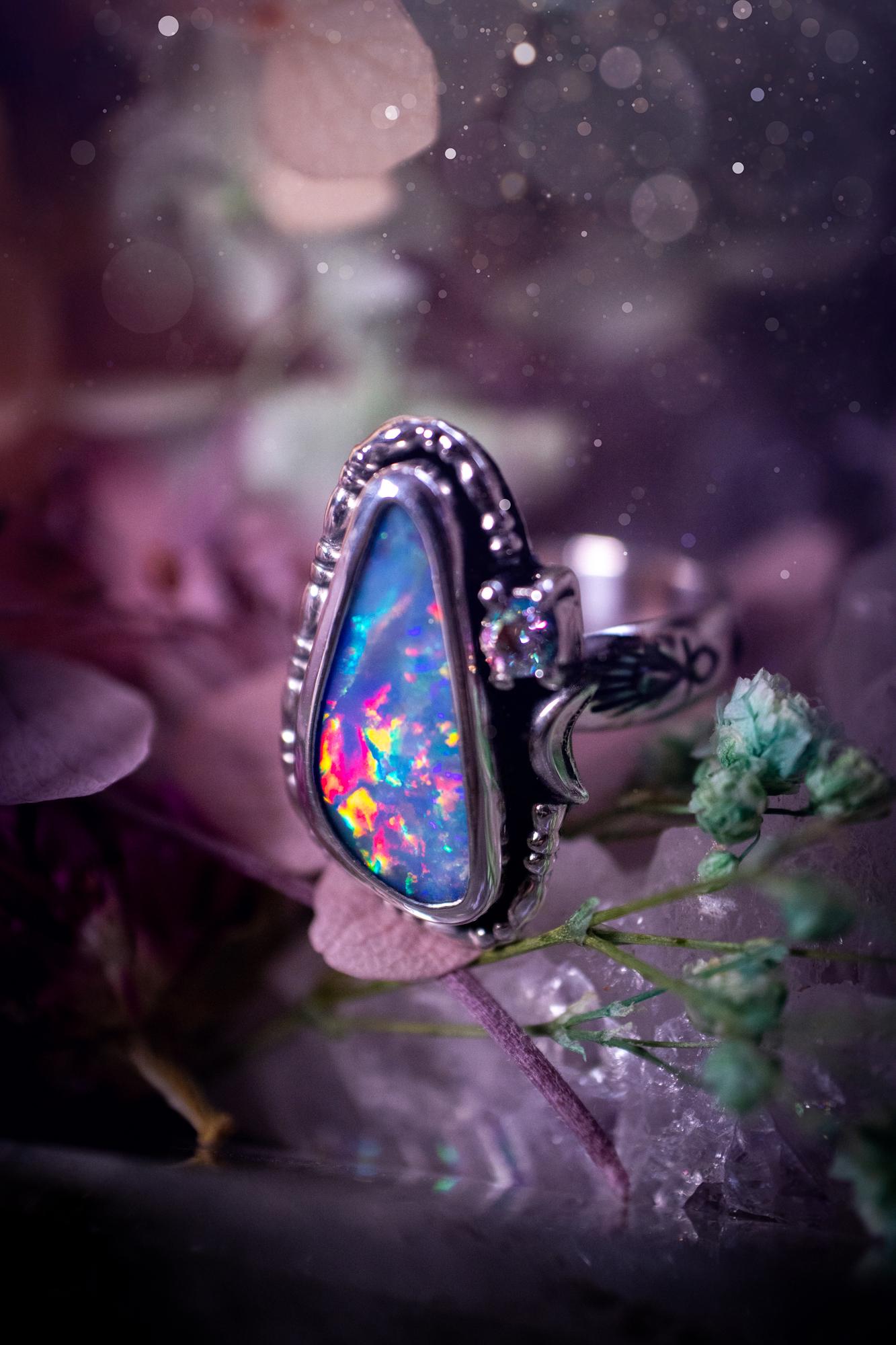Handmade and totally bespoke, Australian Opal doublet, celestial style ring. This mini statement ring has been handmade using fine and sterling silver. Featuring a very beautiful and bold Australian Opal doublet that is full of colour play with lilac, reds, blues and greens that are super flashy! The ring is of a celestial style with a little moon and aurora coloured cubic zirconia to the side. This little ring would be suitable for anyone who loves crystals, opals and jewellery! Gothic vibes