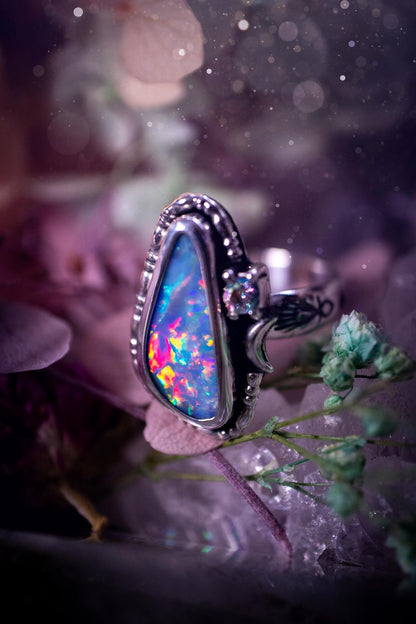 Handmade and totally bespoke, Australian Opal doublet, celestial style ring. This mini statement ring has been handmade using fine and sterling silver. Featuring a very beautiful and bold Australian Opal doublet that is full of colour play with lilac, reds, blues and greens that are super flashy! The ring is of a celestial style with a little moon and aurora coloured cubic zirconia to the side. This little ring would be suitable for anyone who loves crystals, opals and jewellery! Gothic vibes