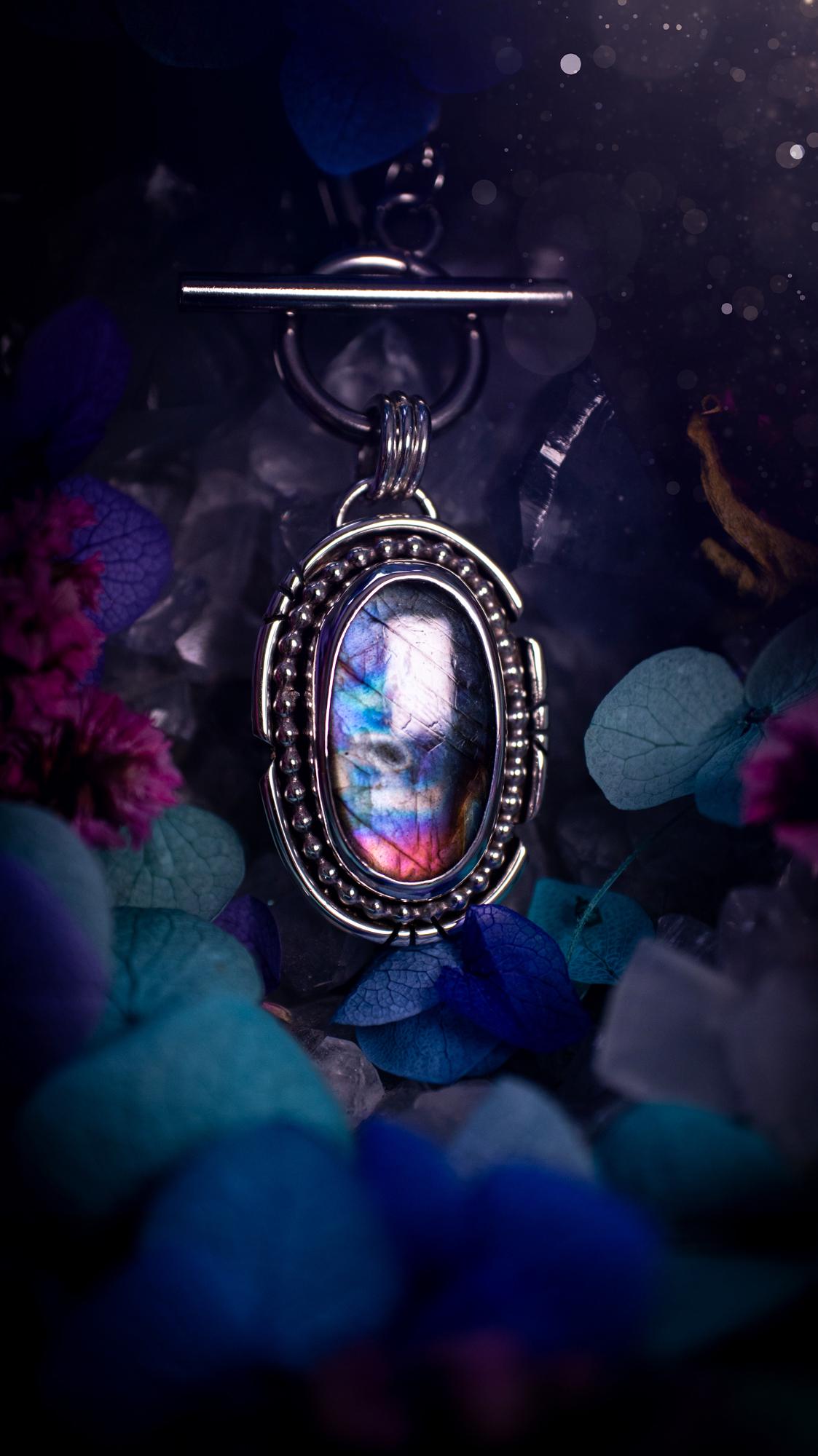 Beautifully handmade, amulet pendant necklace which features the most beautiful rainbow coloured, labradorite spectrolite crystal. This pendant has been handcrafted using a mix of fine and sterling silver. It features a smooth bezel with beaded, and hand carved smooth wire around the stone making this piece totally bespoke and one of a kind. The labradorite has an array of beautiful purples, blues and pinks. This pendant would be suitable for any crystal and jewellery lover, gothic and hippy!